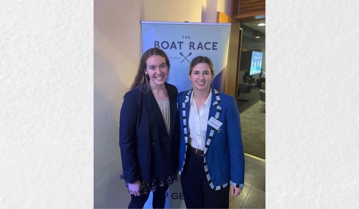 Clara and teammate standing in front of a Boat Race banner