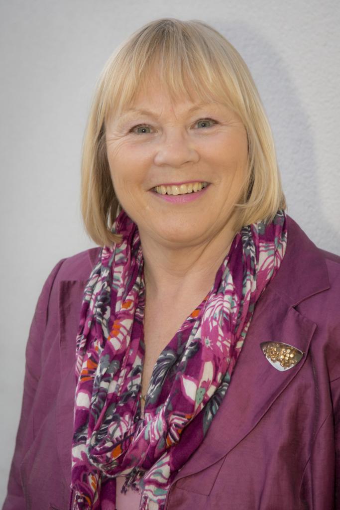 Ann Limb portrait wearing a purple jacket and color coordinated flowery scarf