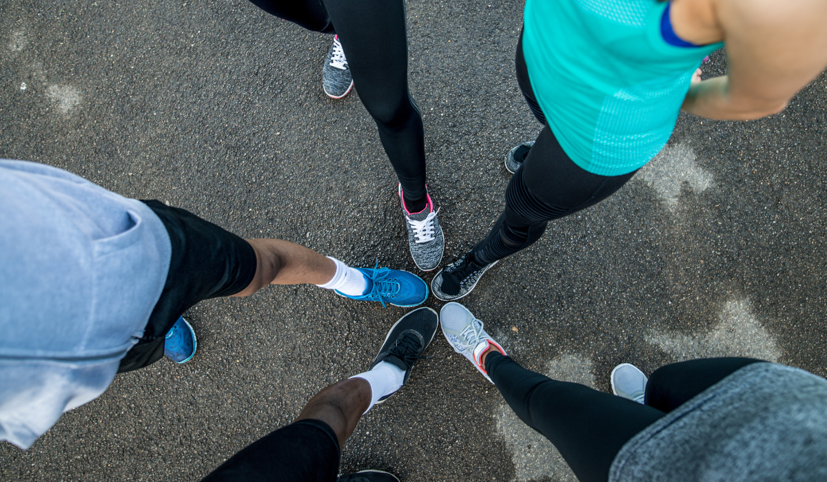 Aerial-like shot of five people in a circle joining feet