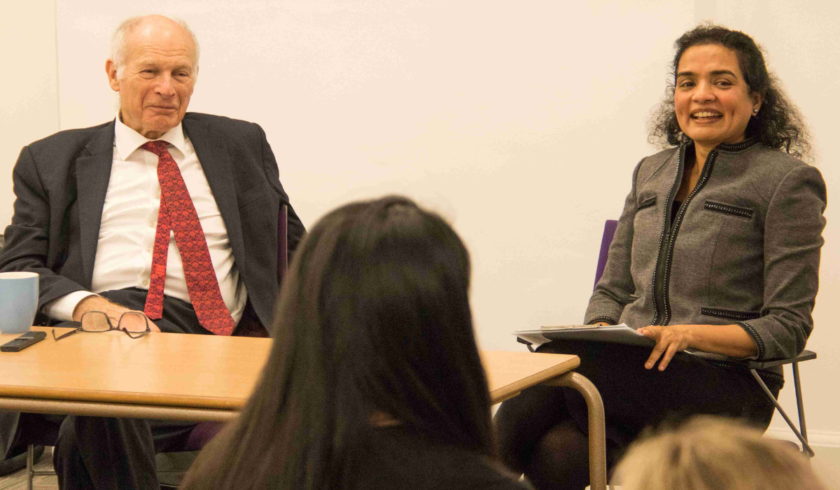 Lord Neuberger with Dr Poorna Mysoor, seated across from each other at a table in front of audience