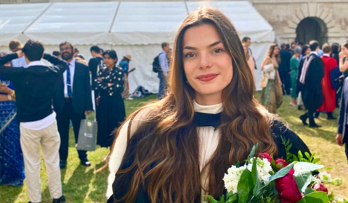 Alexandra posing for photo at the graduation ceremony holdinga a flower bouquet