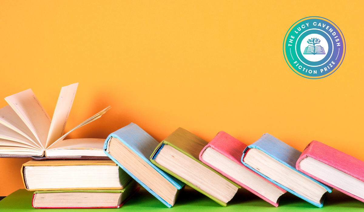 A row of colorful hardcover books arranged in a leaning stack on a bright orange background. One book is open, standing upright with pages fanned. In the top right corner is a circular logo that reads "The Lucy Cavendish Fiction Prize" around an icon of an open book.