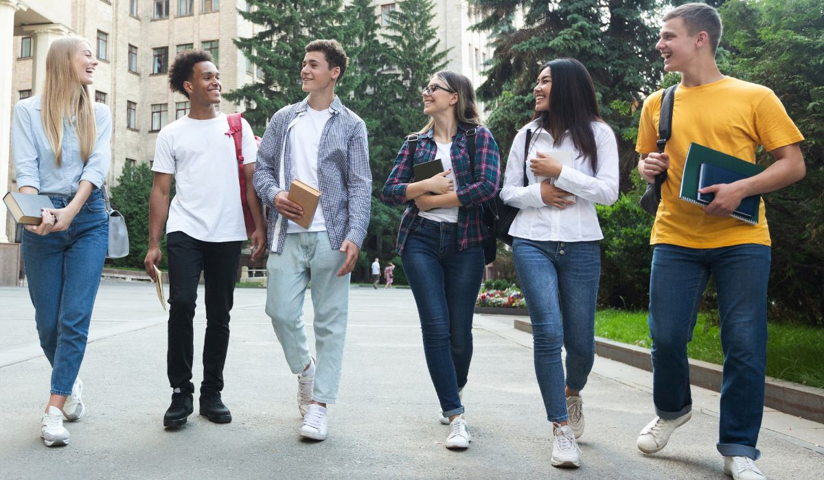 Mixed group of six students walking and talking on university campus