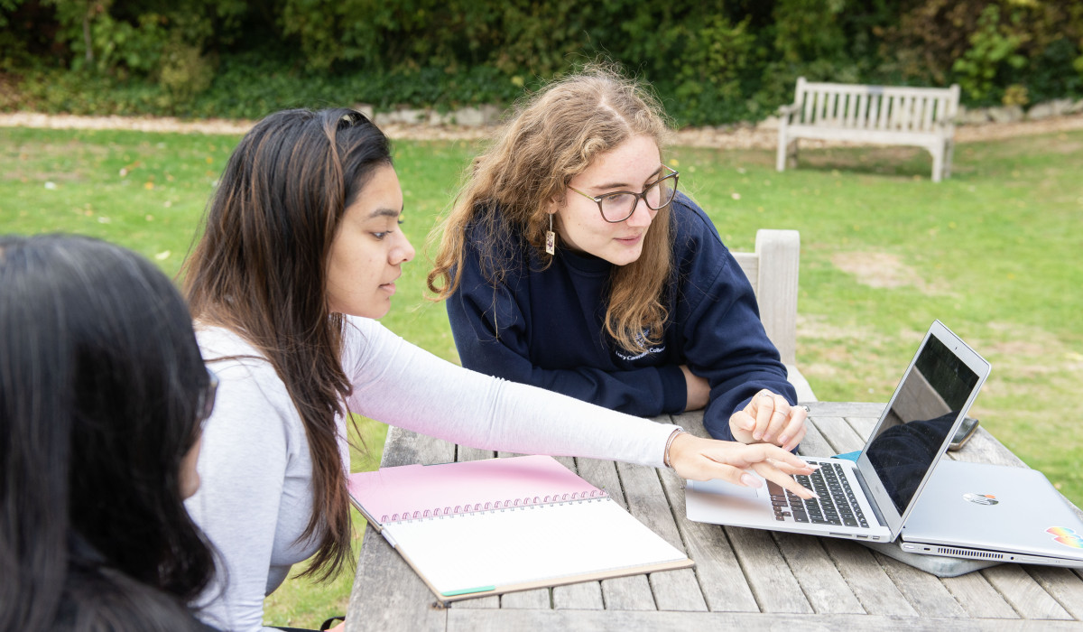 Lucy students working together on a loptop in the College gardens