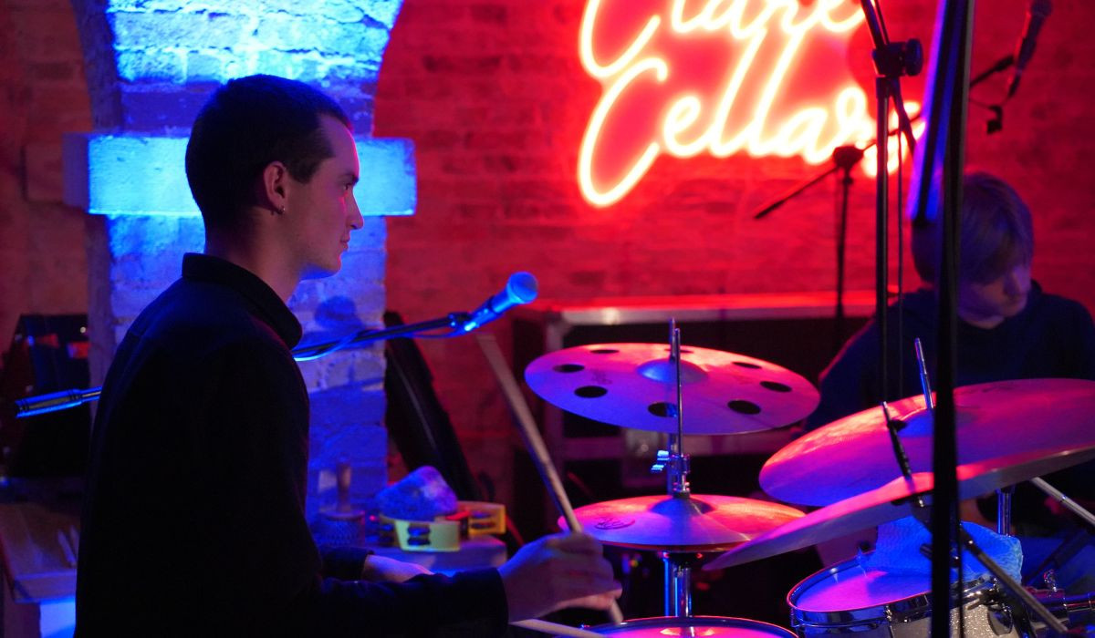 Wynn Tasker playing drums in neon-lit room