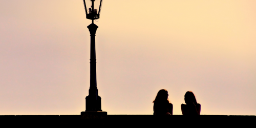 Two women talking on bridge at sunset