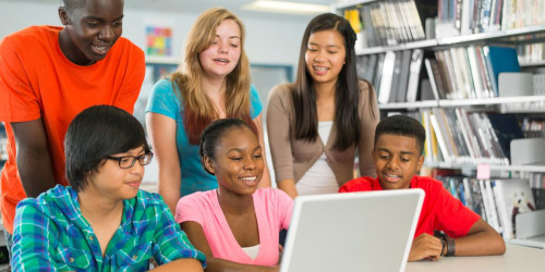 Diverse group of teenage students collaborating on laptop