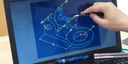 The image shows a close-up of a person's hand using a laptop computer and a pen to create a digital drawing.