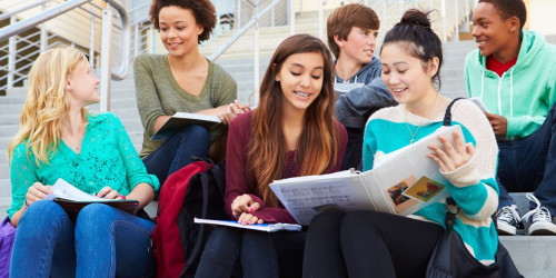 Group of mixed students sitting on stairs working