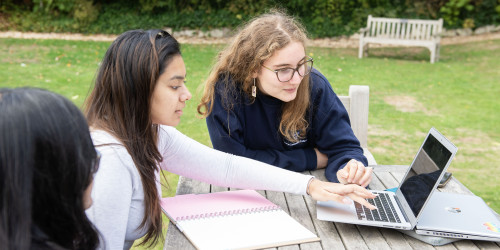 Lucy students working together on a loptop in the College gardens