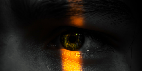 Close up of person's face with eye illuminated by strip of light 